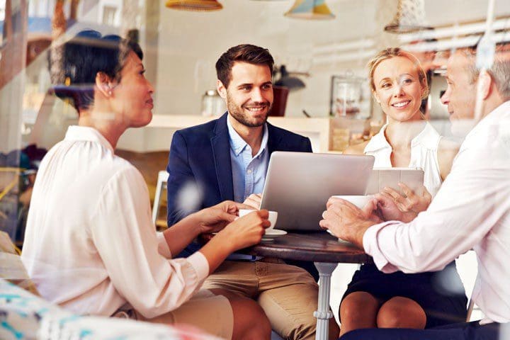 group of adults sitting in a coffee shop discussing clear goals to set for their website